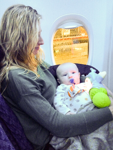 Baby resting in mother’s arms on an Airplane Baby resting in mother's arms on an Airplane